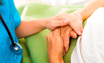 nurse holding the hand of an elderly patient