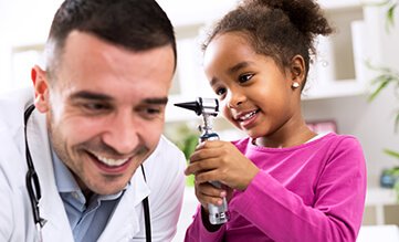 doctor laughs while child inspects his ear